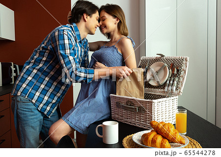 Smiling pregnant woman hugging with husband in kitchen 65544278