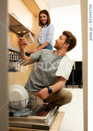 Happy male taking dishes out of dishwasher Happy male taking dishes out of dishwasher 65544750