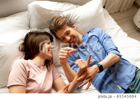 Smiling lovers touching hands of each other in bed room 65545004