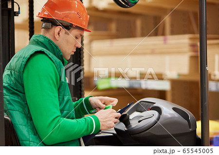 confident warehouse worker sitting inside of cab 65545005