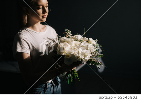 Cute blonde young woman wearing fashion clothes holding wonderful composition of fresh flowers 65545803