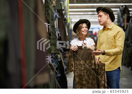 young man and woman in search of equipment for hunting in store young man and woman in search of equipment for hunting in store 65545925