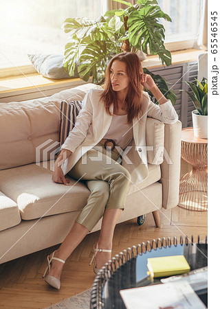 Elegant woman in business attire sitting on sofa with her legs crossed Elegant woman in business attire sitting on sofa with her legs crossed 65546545