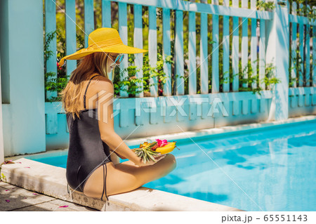 Young woman relaxing and eating fruit plate by the hotel pool. Exotic summer diet. Photo of legs Young woman relaxing and eating fruit plate by the hotel pool. Exotic summer diet. Photo of legs 65551143