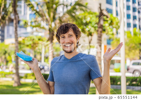 Quarantine is over concept. Man taking off mask against the background of small town houses. We are Quarantine is over concept. Man taking off mask against the background of small town houses. We are 65551144