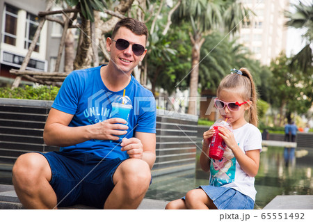 Vietnam, Ho Chi Minh, January 2020. Young girl with her dad have fun, drinking fruit ice Froster Vietnam, Ho Chi Minh, January 2020. Young girl with her dad have fun, drinking fruit ice Froster 65551492