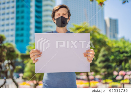 Man in medical mask prevents coronavirus disease holds a poster for free inscriptions. COPY SPACE 65551786