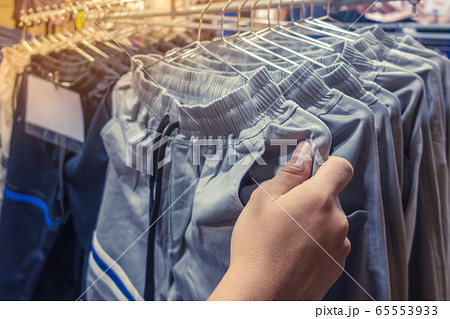 People check and choose pants to buy on hangers in a clothing store. 65553933