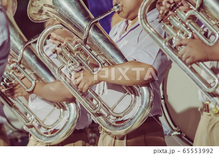 Male student with friends blow the euphonium with the band for performance on stage at night. 65553992