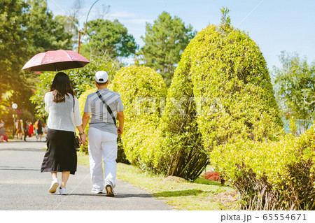 Back view of man and woman in love walking together in spring garden, having fun outdoors, relaxation on backyard, romance and love concept Back view of man and woman in love walking together in spring garden, having fun outdoors, relaxation on backyard, romance and love concept 65554671