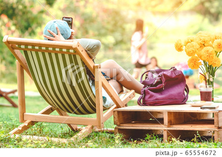 Backview of happiness woman on a summer holiday sitting on garden chair to relax in the public park. Backview of happiness woman on a summer holiday sitting on garden chair to relax in the public park. 65554672