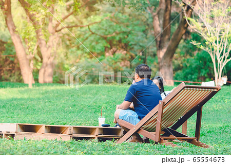 Happiness couple on a summer holiday sitting on garden chairs to relax in the public park. Happiness couple on a summer holiday sitting on garden chairs to relax in the public park. 65554673