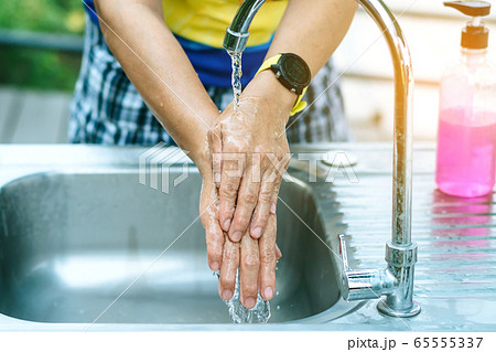 A woman washing hands from the tap with pink soap in a aluminium tub. Concepts of Flu virus, Covid-19 (Coronavirus disease). Selective focus. 65555337