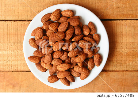 Almonds nuts on white plate on wooden background , 65557488