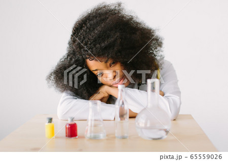 Laboratory work. Portrait of a young beautiful African American girl researcher chemistry student carrying out research in a chemistry lab. 65559026