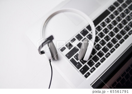 Top view of laptop, white headphones with microphone on table . 65561791