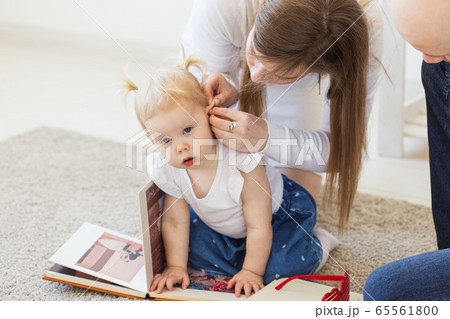 Hearing aid in baby girl's ear. Toddler child wearing a hearing aid at home. Disabled child, disability and deafness concept. Hearing aid in baby girl's ear. Toddler child wearing a hearing aid at home. Disabled child, disability and deafness concept. 65561800