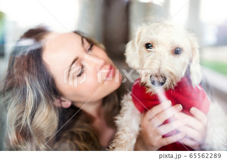 Young woman relaxing indoors at home with pet dog. Shot through glass. Young woman relaxing indoors at home with pet dog. Shot through glass. 65562289