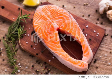 Fresh salmon fillet on a board, food close up top view. Diet, omega vitamins and seafood concept. Fresh salmon fillet on a board, food close up top view. Diet, omega vitamins and seafood concept. 65562290