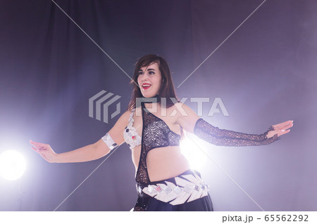 Young woman belly dancer in exotic dress with gold, dancing tribal fusion dance in studio. 65562292