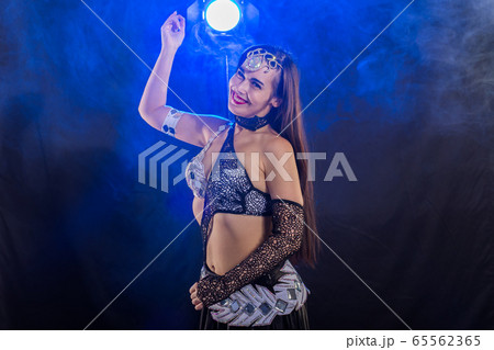 Young woman belly dancer in exotic dress with gold, dancing tribal fusion dance in studio. 65562365