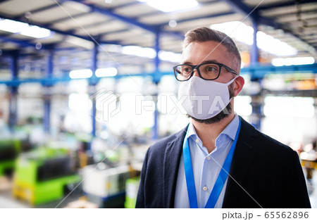 Technician or engineer with protective mask standing in industrial factory. 65562896