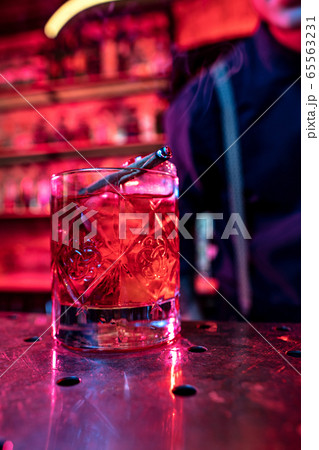 Close up of alcoholic cocktail, beverage, drink, glass full of ice in multicolored neon light Close up of alcoholic cocktail, beverage, drink, glass full of ice in multicolored neon light 65563231