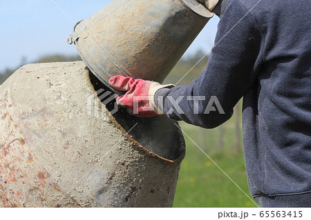 Construction worker mixing ingredients in the concrete mixer at building site 65563415