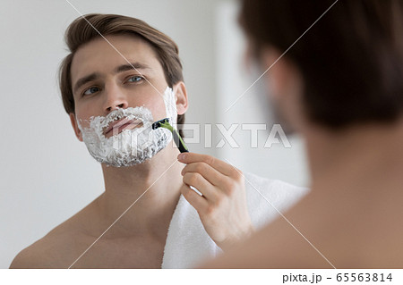 Caucasian man look in bat mirror shaving in morning 65563814