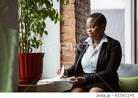 African-american businesswoman in office attire smiling, looks confident and happy, successful African-american businesswoman in office attire smiling, looks confident and happy, successful 65567245