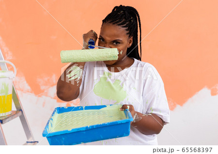 Angry african american woman painting interior wall of new house. Redecoration, renovation, apartment repair and refreshment concept. 65568397
