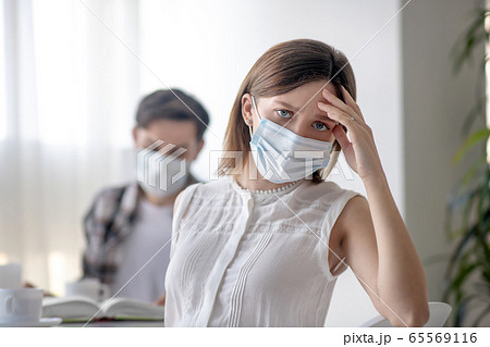 Young woman in a facial mask having a headache Young woman in a facial mask having a headache 65569116
