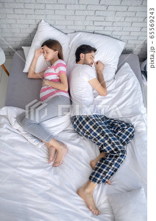 Pregnant young woman in a striped tshirt and her husband napping 65569243