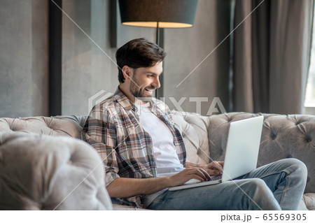Young adult man with laptop on the couch. Young adult man with laptop on the couch. 65569305
