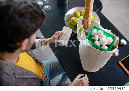 Young bearded man looking at the bill in his hand 65569982