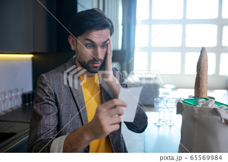 Young bearded man in a yellow tshirt looking astonished 65569984