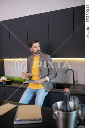 Young bearded man holding an envelope in his hand and looking thoughtful 65570011