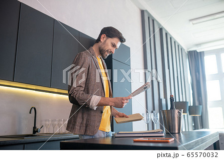 Young bearded man holding an envelope in his hand and looking involved Young bearded man holding an envelope in his hand and looking involved 65570032