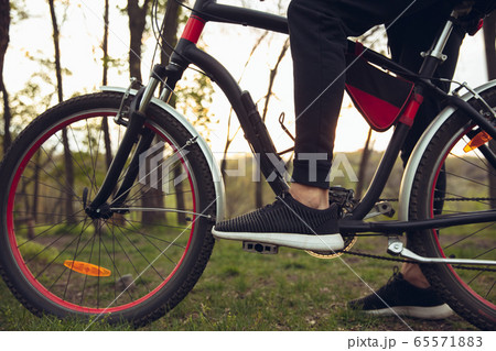 Close up of young man having fun near countryside park, riding bike, traveling at spring day 65571883