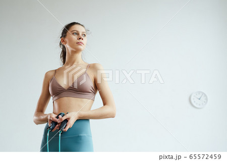 Portrait of Sportive Young Woman Holding Jumping Rope 65572459