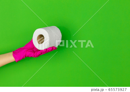 Hand in pink rubber glove with toilet paper isolated on green studio background with copyspace. 65573927