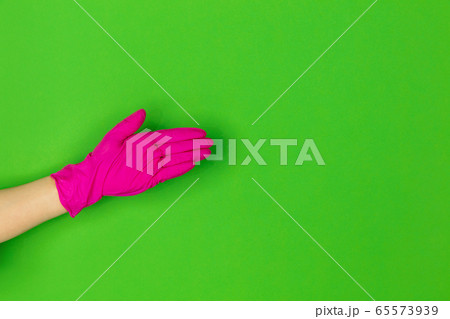 Hand in pink rubber glove greeting isolated on green studio background with copyspace. 65573939