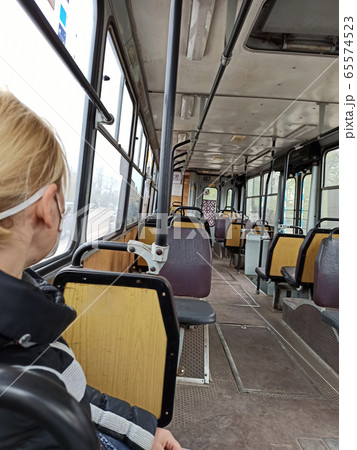 woman in mask riding in empty trolley bus during 65574523