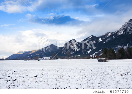 Wooden shed in snowy field against Alps in winter 65574716