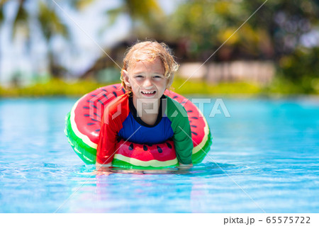 Child in swimming pool on toy ring. Kids swim. 65575722