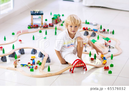 Kids play wooden railway. Child with toy train. Kids play wooden railway. Child with toy train. 65576032