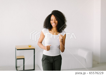 An African American young woman doing physical exercises standing in a mat An African American young woman doing physical exercises standing in a mat 65576229
