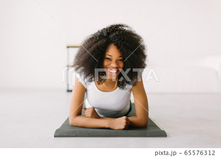 An African American young woman doing physical exercises in a mat 65576312
