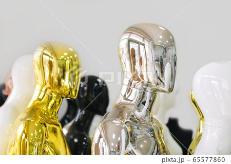 White, black, golden, silver mannequins stand in a row one after another. Concept of a faceless crowd. White, black, golden, silver mannequins stand in a row one after another. Concept of a faceless crowd. 65577860