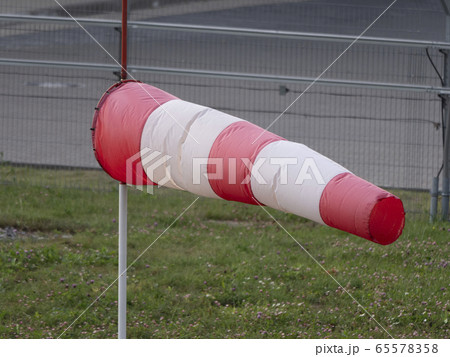 Frayed windsock in moderate wind against blue sky Frayed windsock in moderate wind against blue sky 65578358